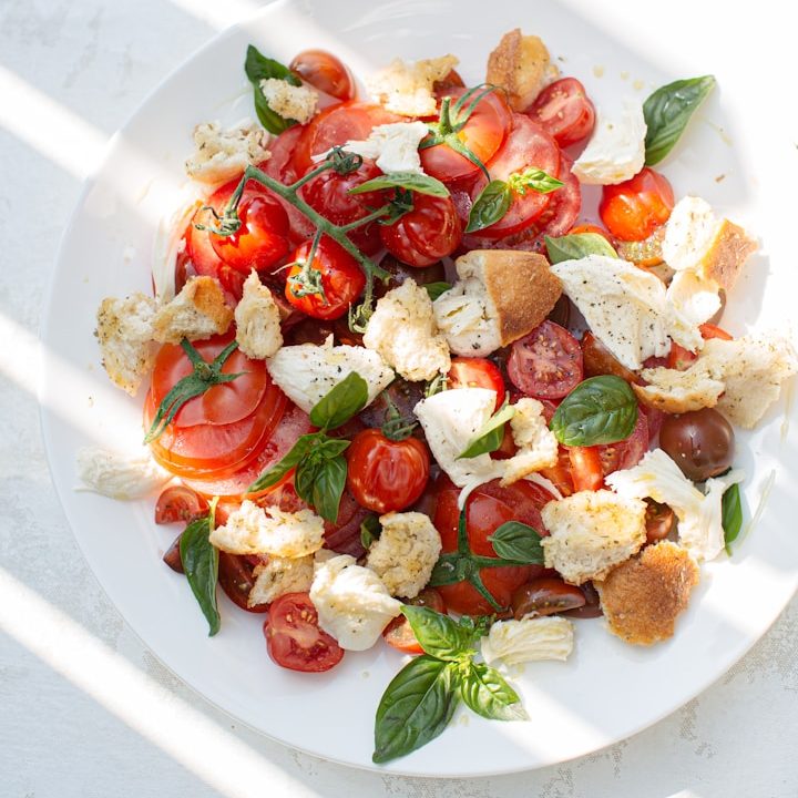 Unplash Teller mit gegrillten Cocktailtomaten am Stiel, Weißbrotwürfeln und Basilikumblättern