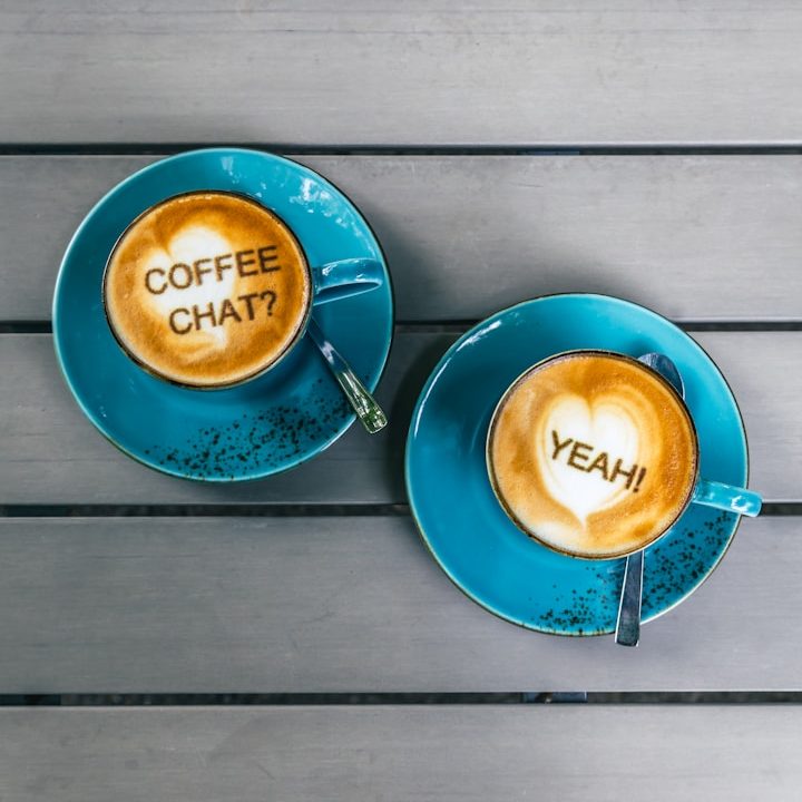 Frank Leuderalbert, unplash Zwei türkise Cappuccino Tassen, in der linken steht im Schaum "Coffee chat" in der rechten "Yeah"